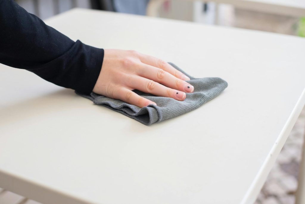 A person wiping a table indoors with a cloth, emphasizing cleanliness and work.