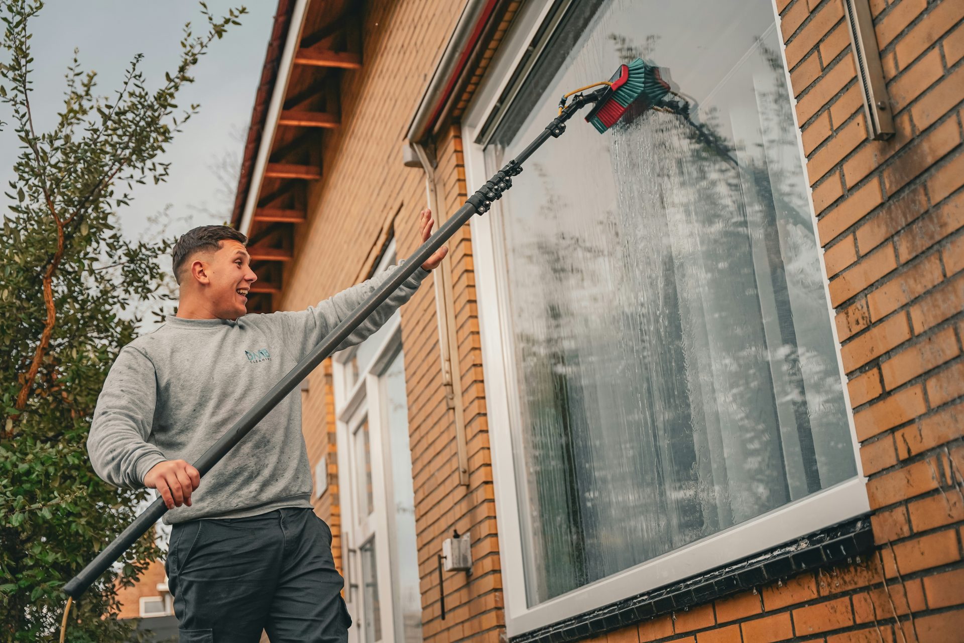 A man holding a large metal pole in front of a house
